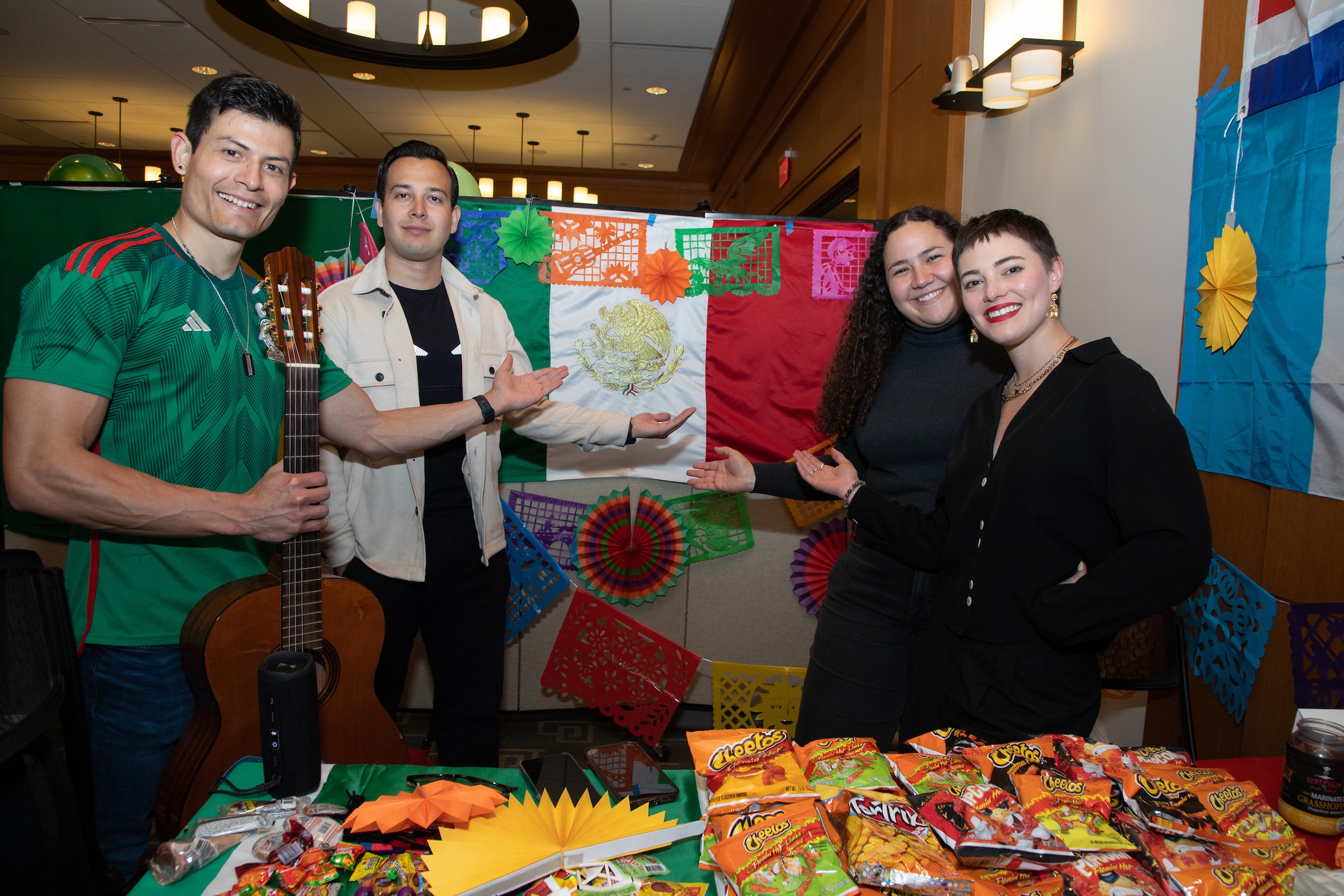 Four students stand at a table with food from their country