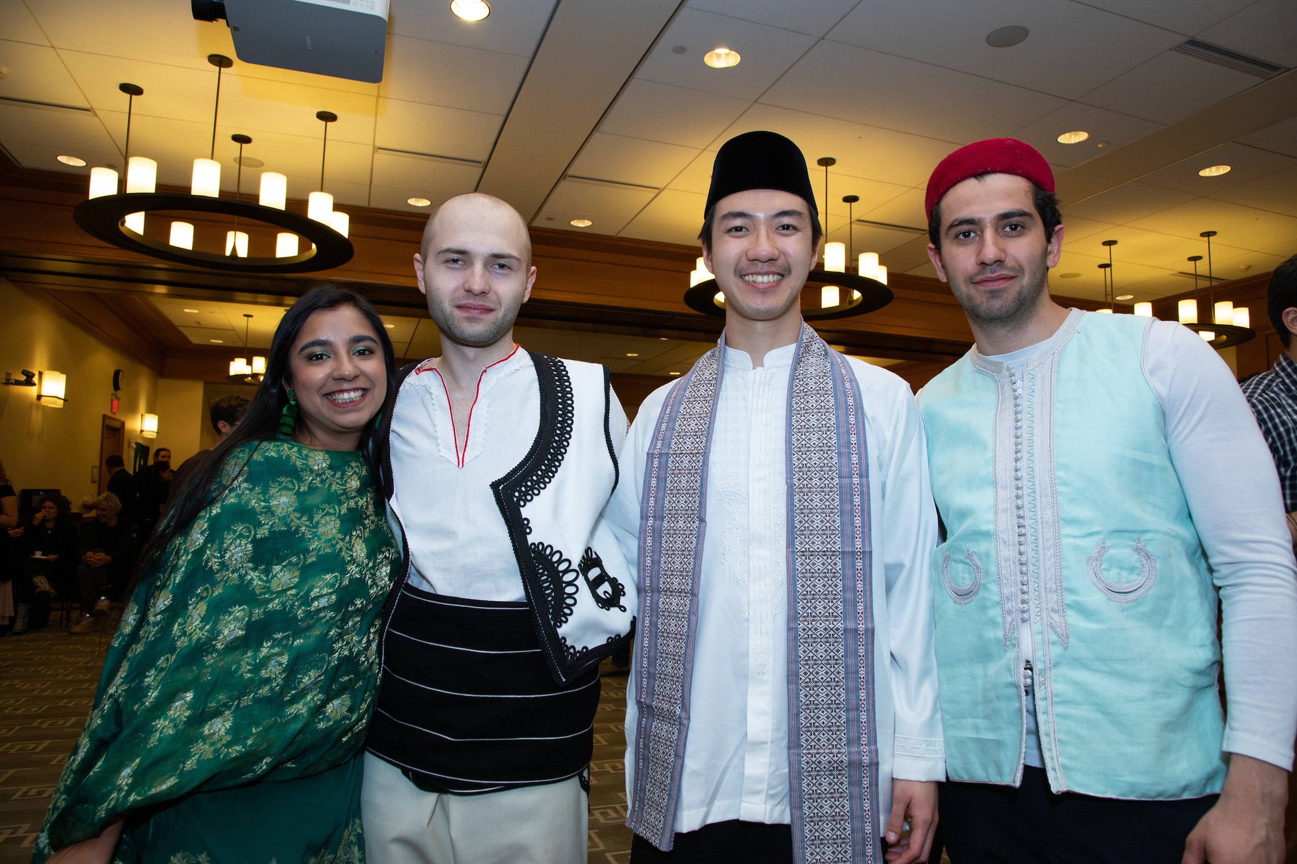 Four people pose in clothing from their country