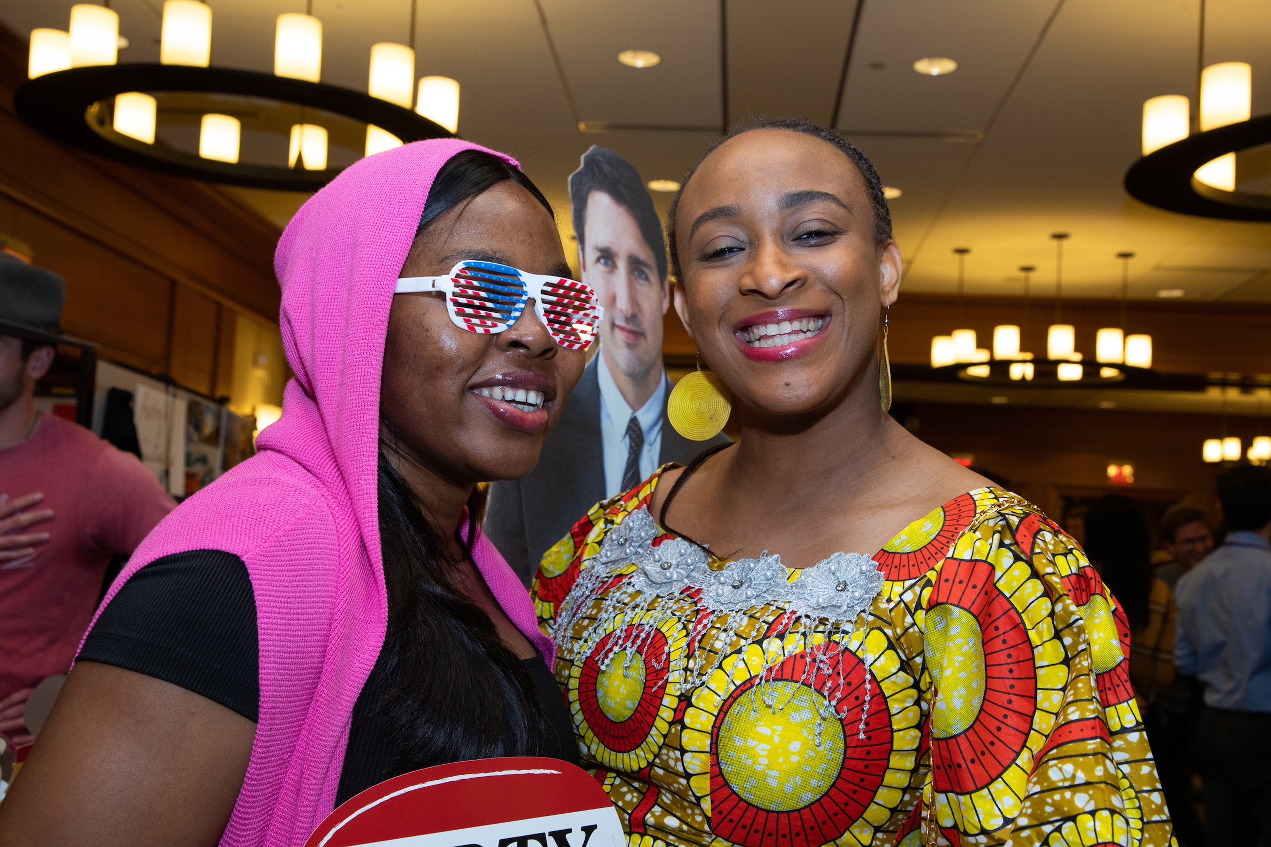 A woman wearing fun glasses poses with another woman at a party