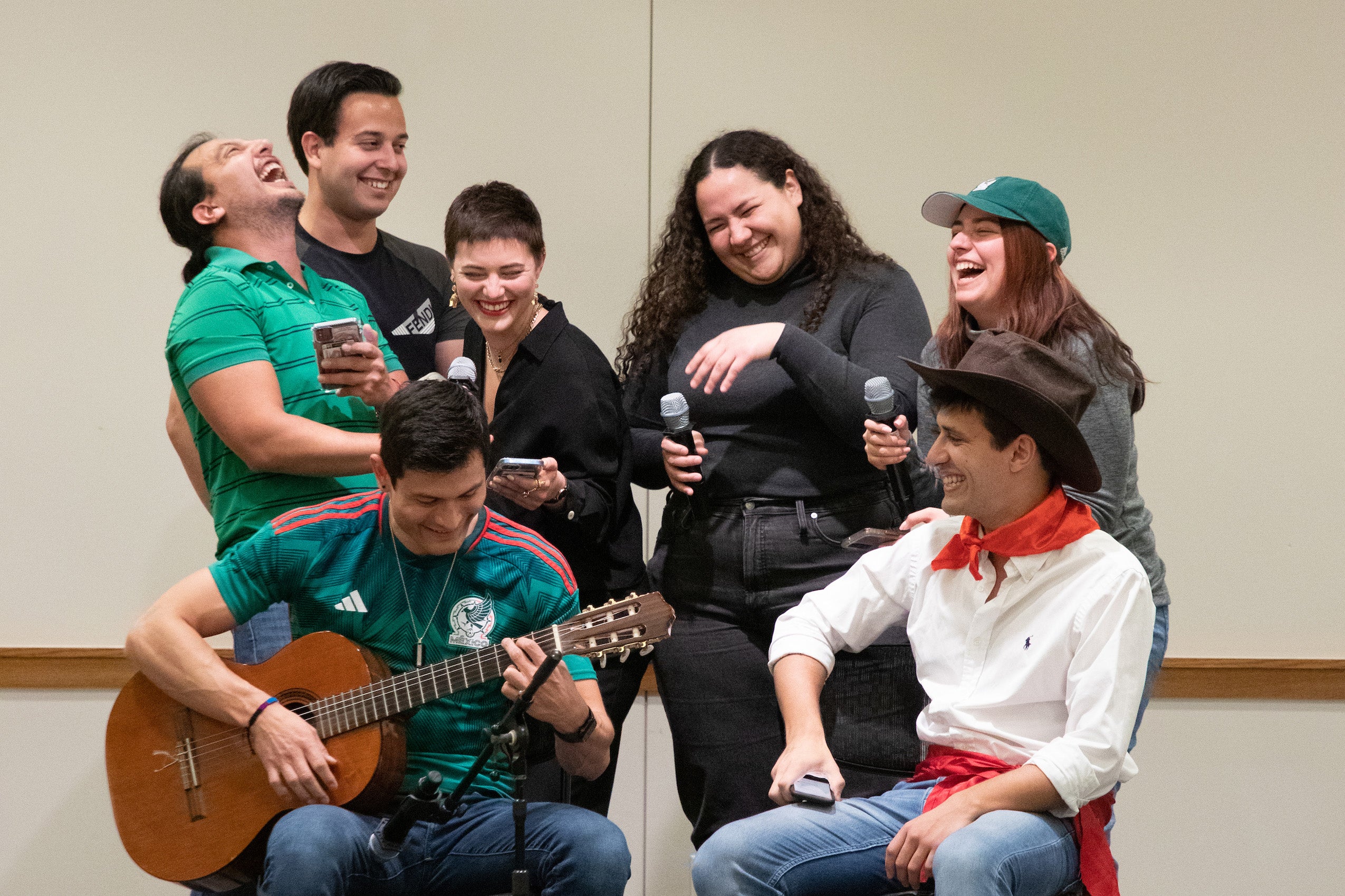 A group of students sing with a guitarist on a stage