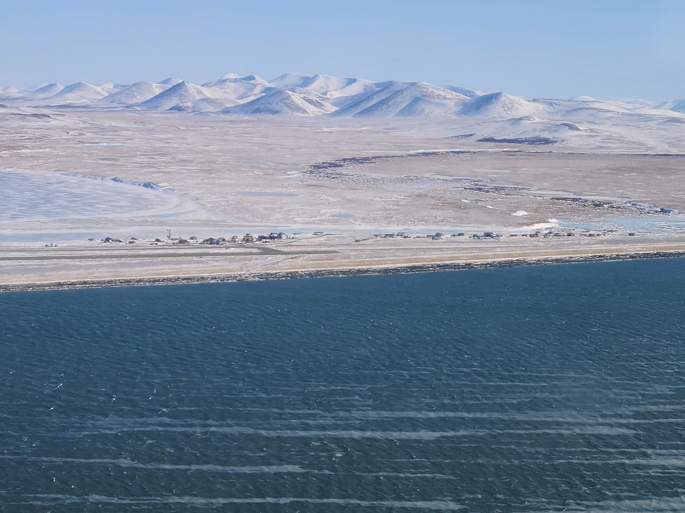 A view of a town near a body of water with snowcovered mountains in the background