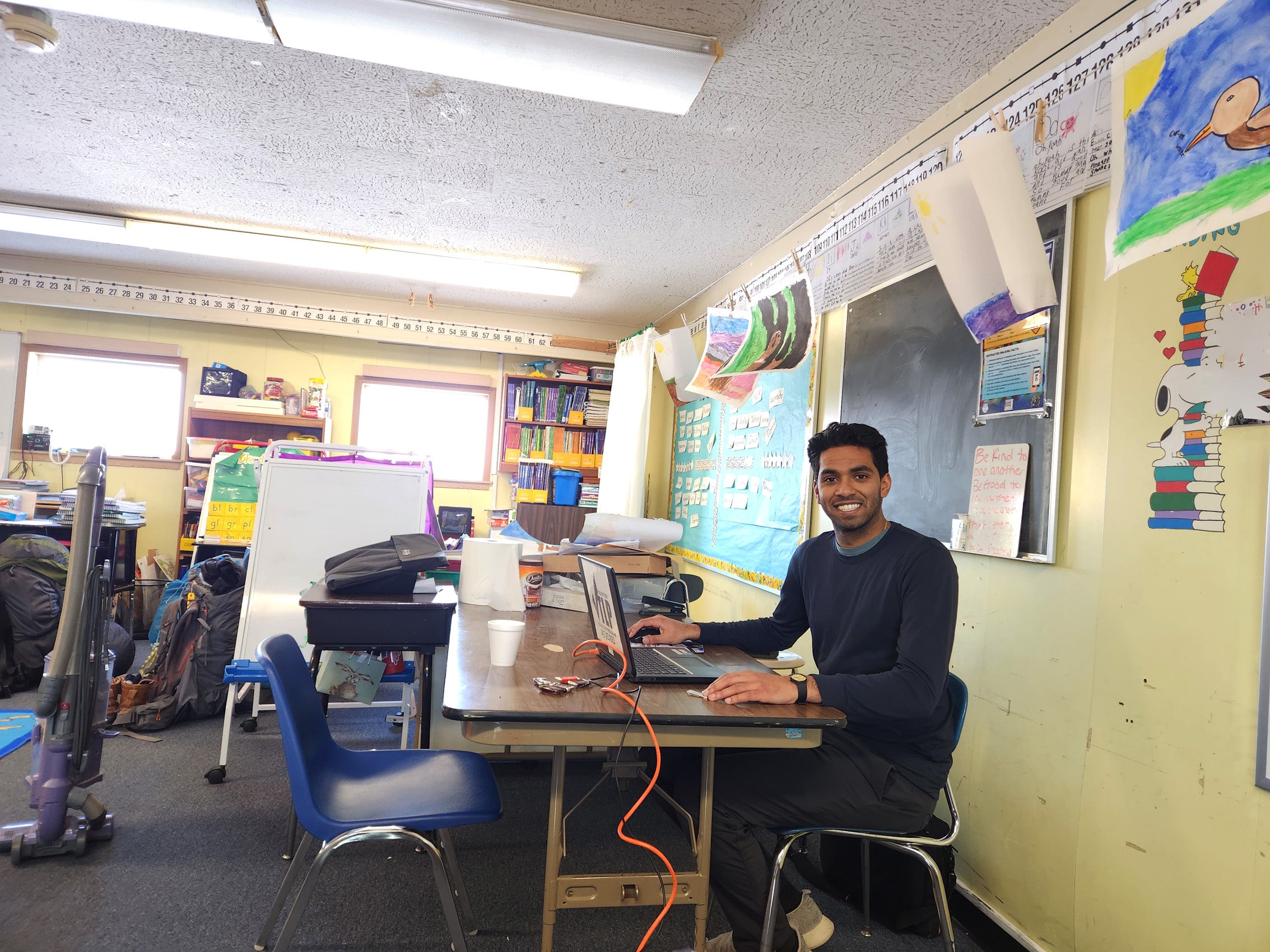 A student sitting in a classroom behind his laptop