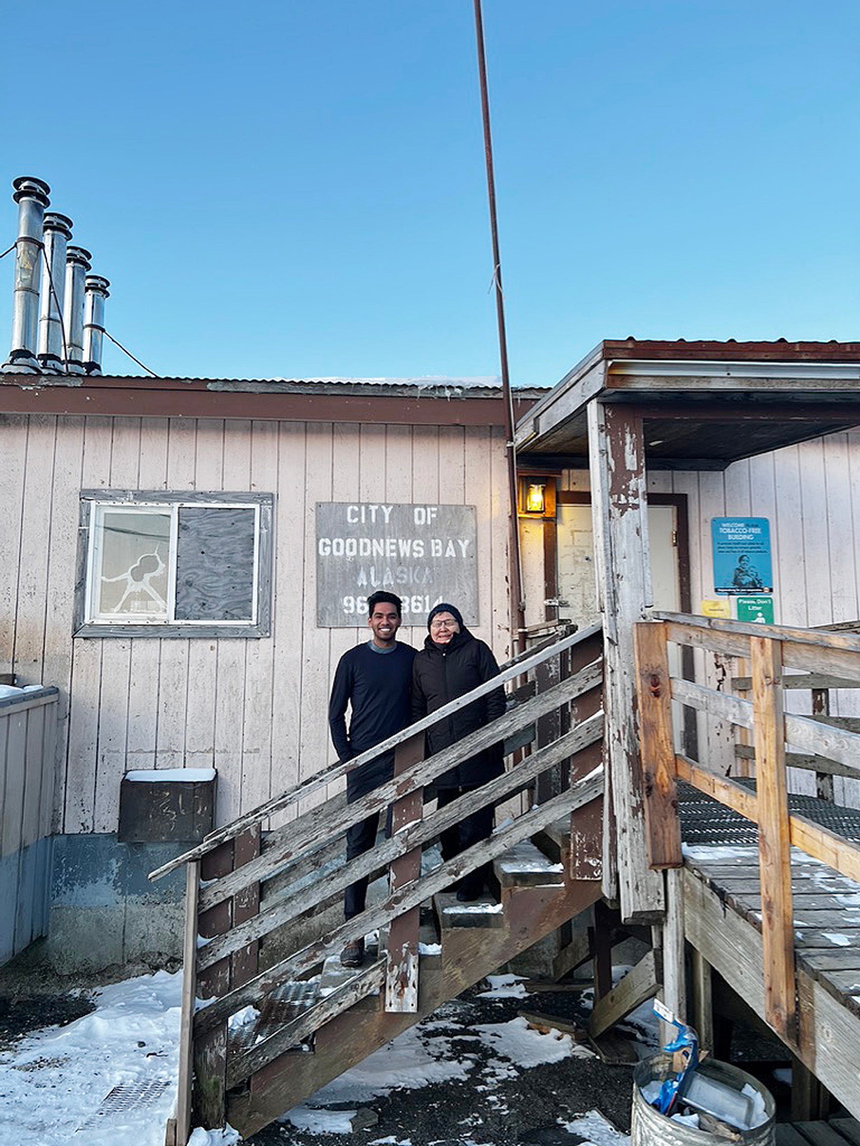 Two people standing on the steps of a wooden building in Goodnews Bay