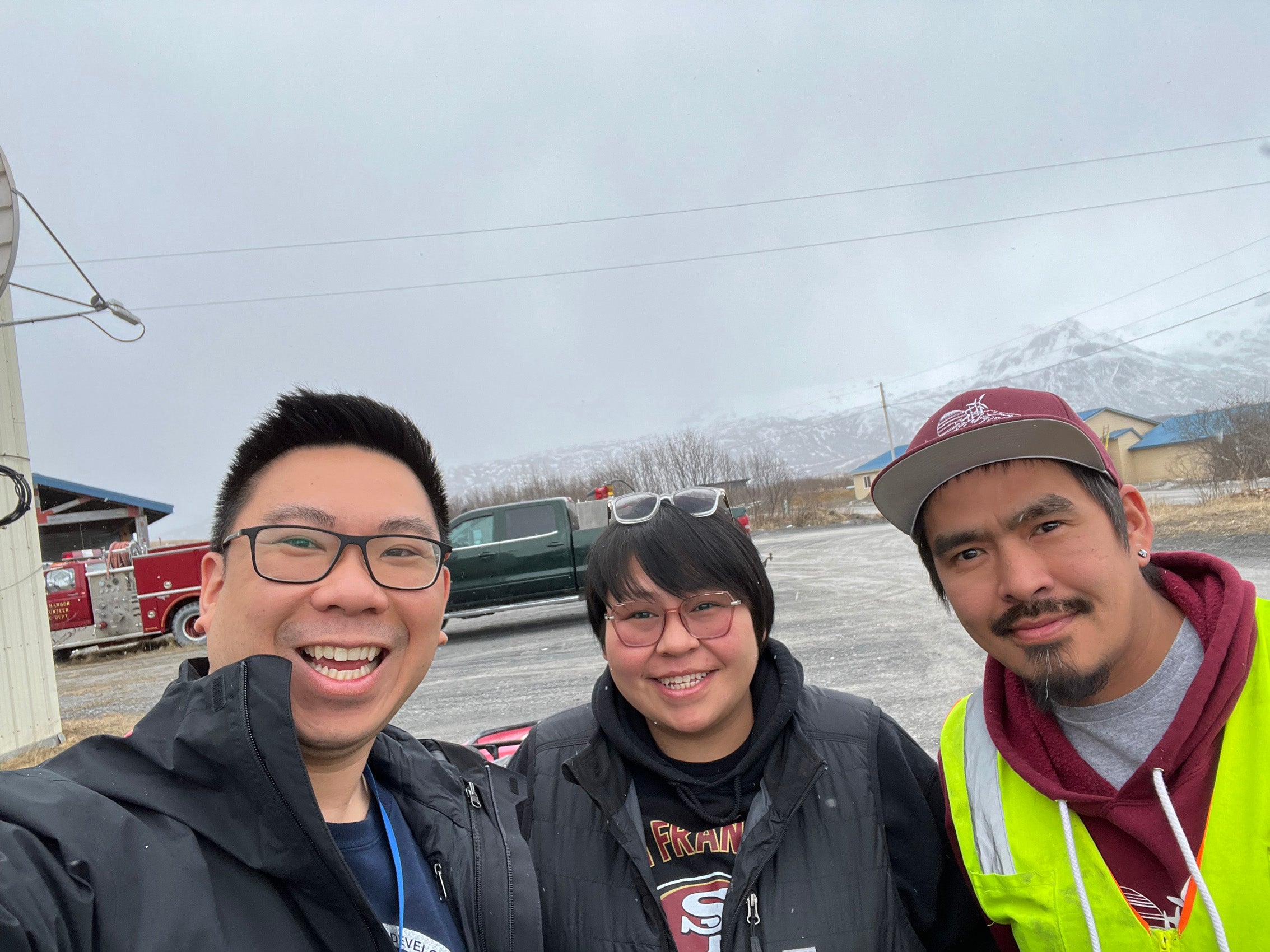 Three people taking a selfie with snow-covered mountain in the background