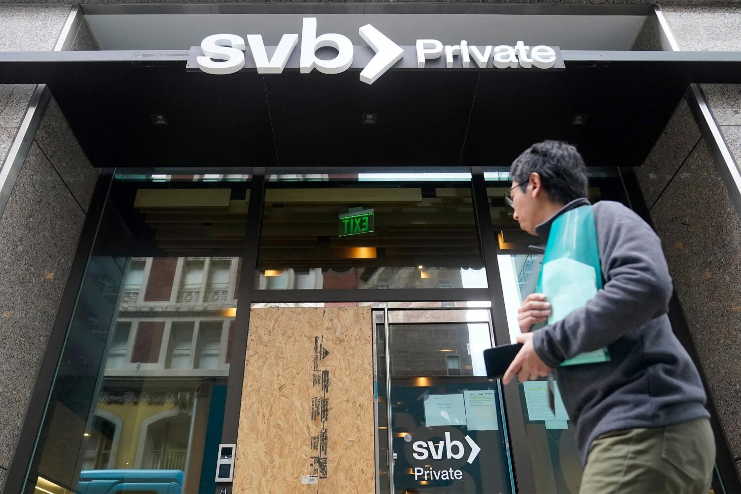 A person walks by a closed SVB branch entrance.