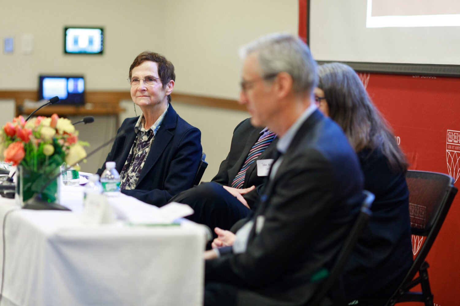 Deborah Anker sits at a table with three other panelists.