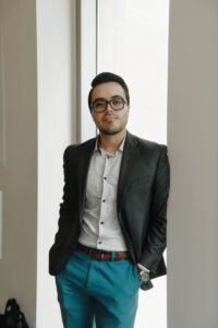 Man leaning against a wall in front of a window