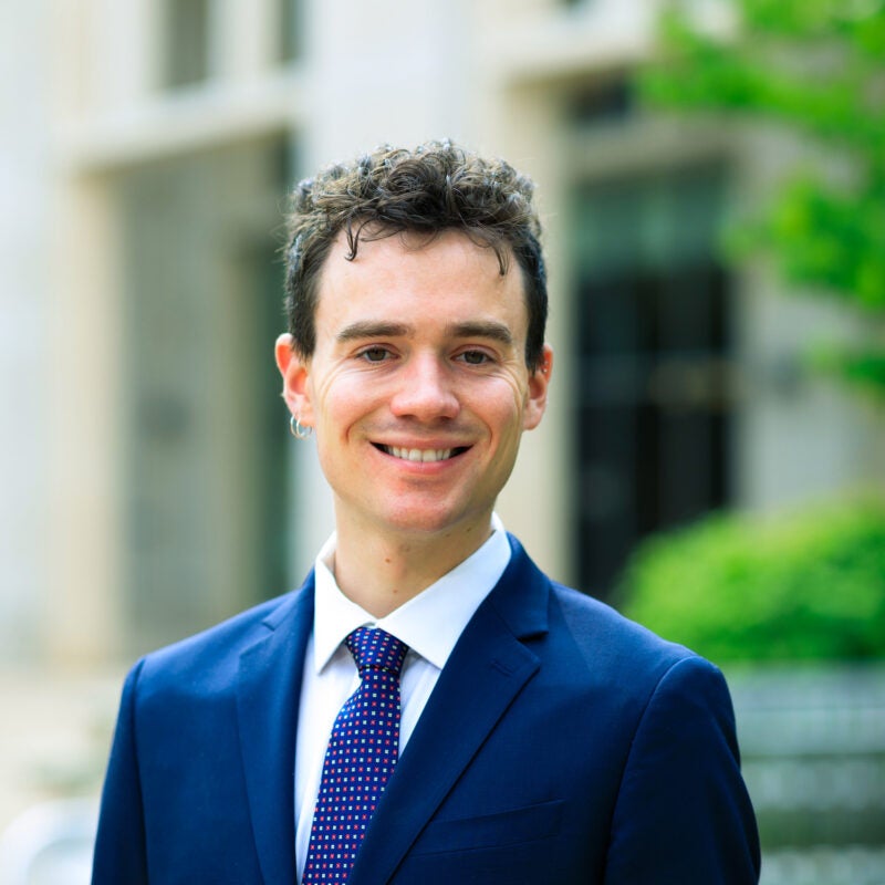 A portrait of Alex Ropes wearing a blue blazer.
