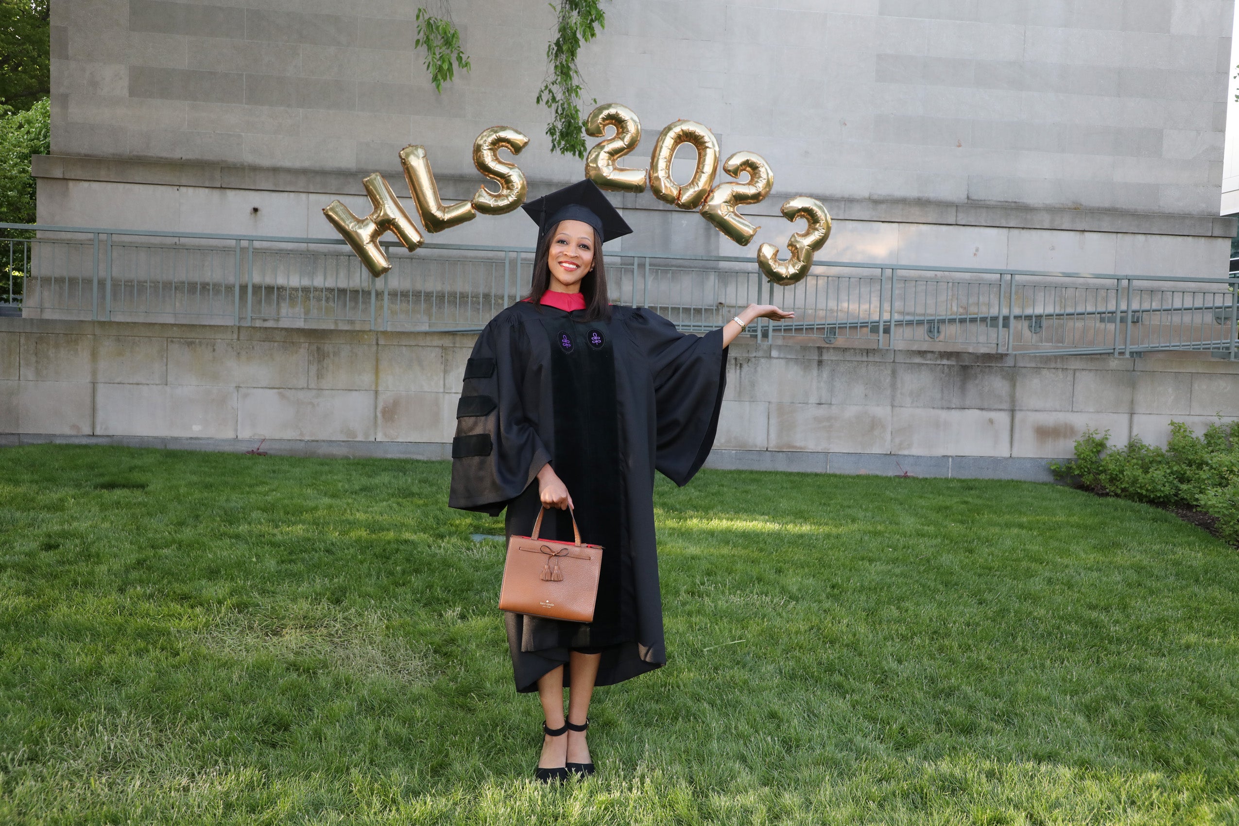 Female graduate poses under HLS 2023 balloons
