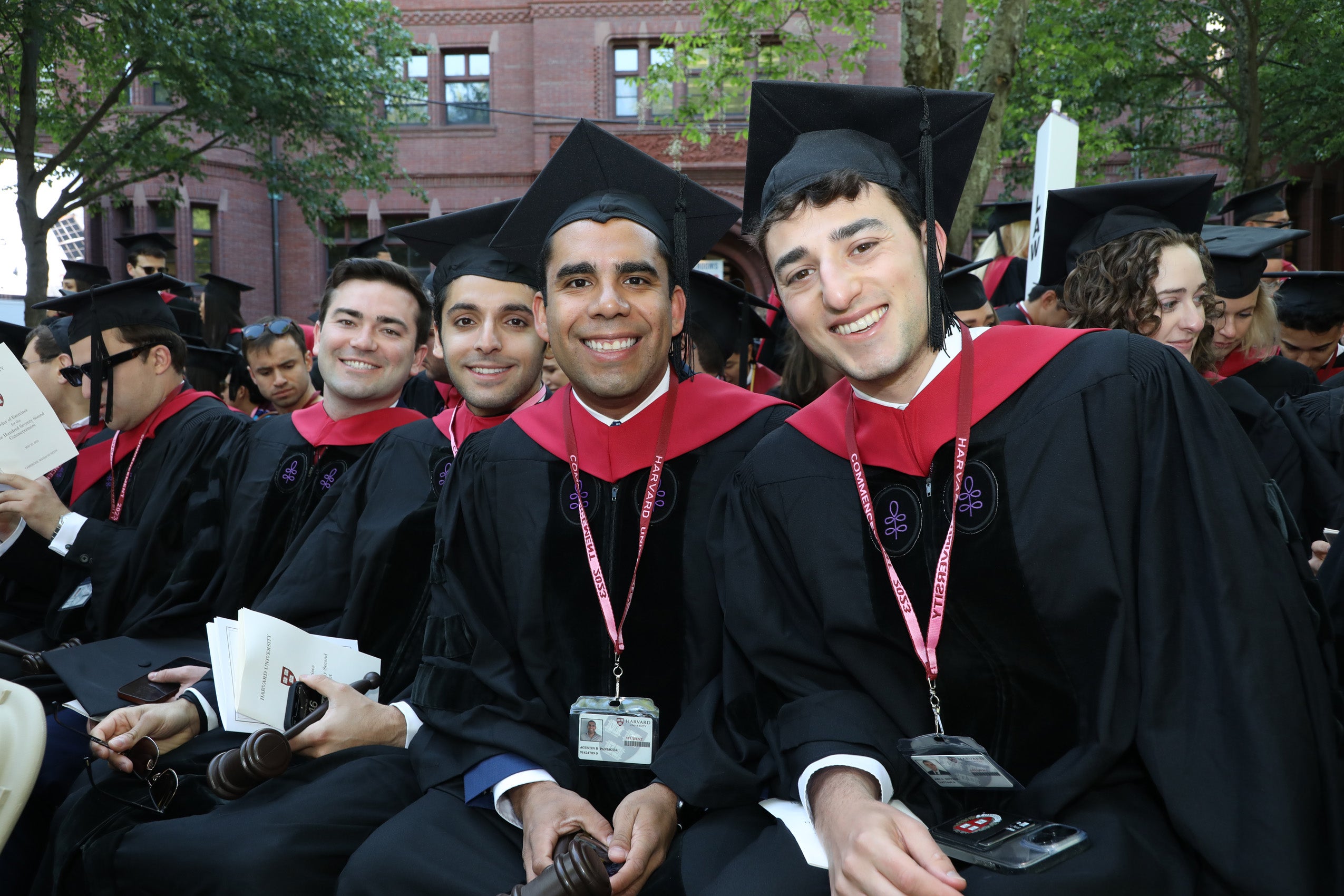 Male students wearing regalia smile