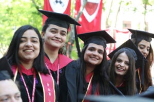 Four women wearing regalia smile at commencement