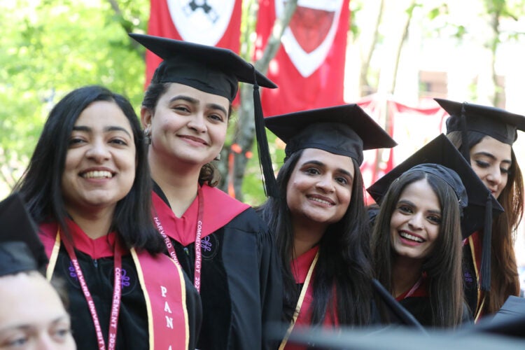 Four women wearing regalia smile at commencement