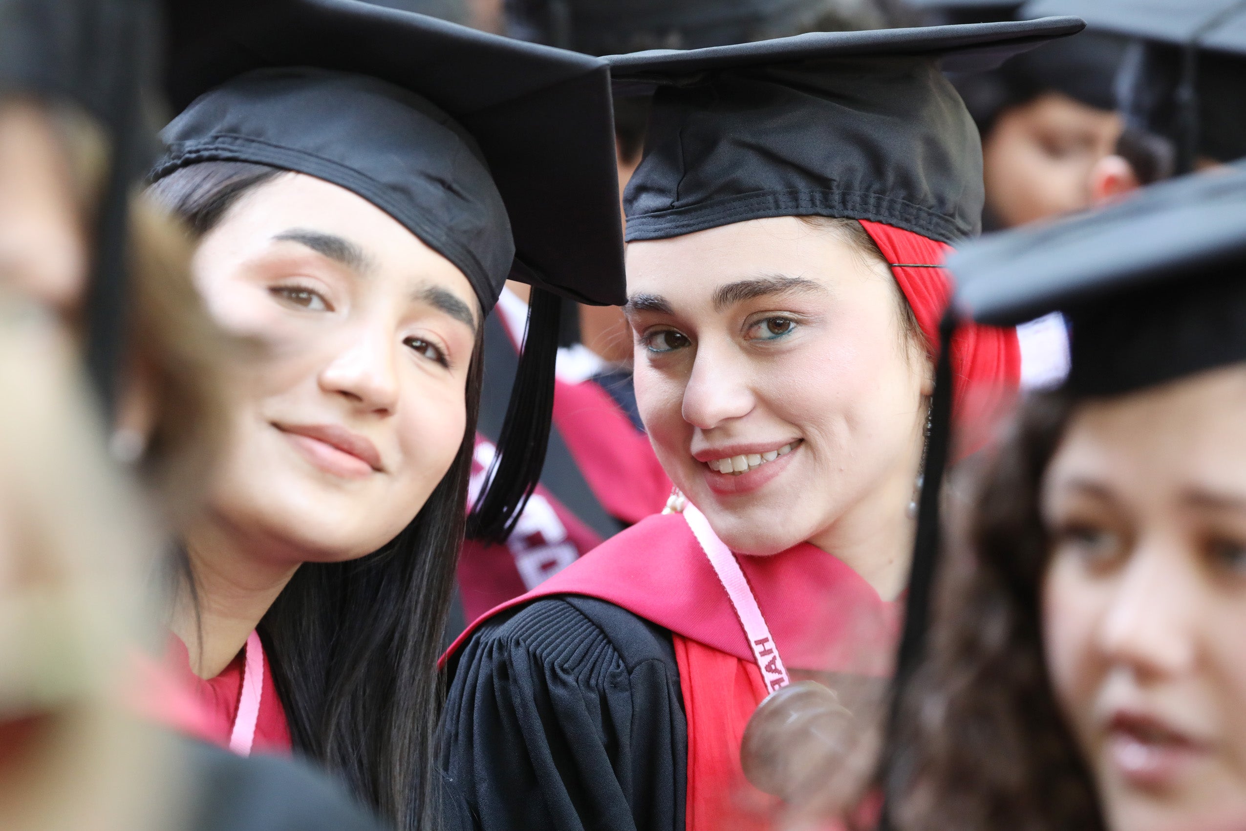 Two women peek through the crowd during commencement ceremony