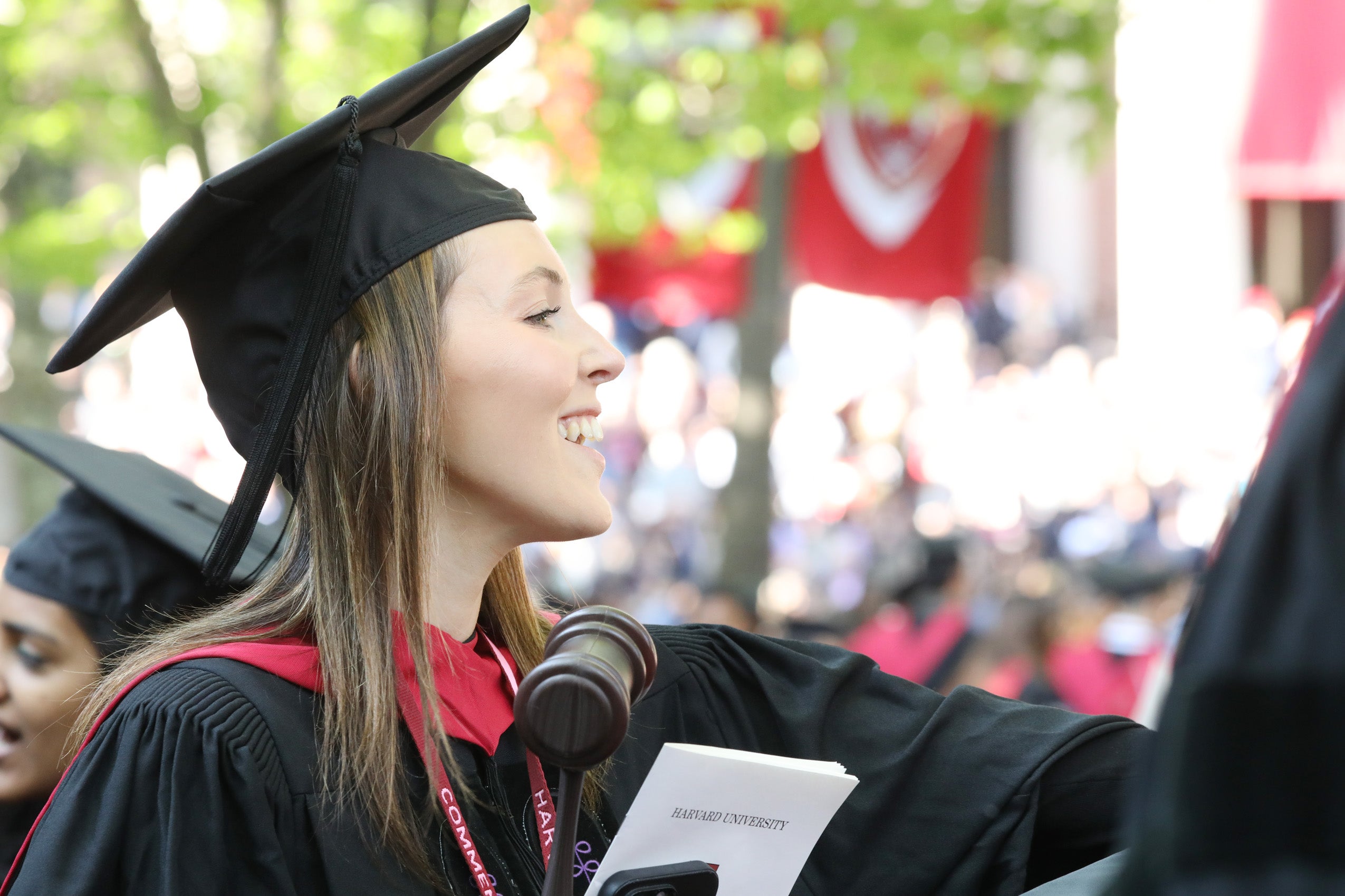 Woman wearing regalia and holding a gavel looks onto crowd