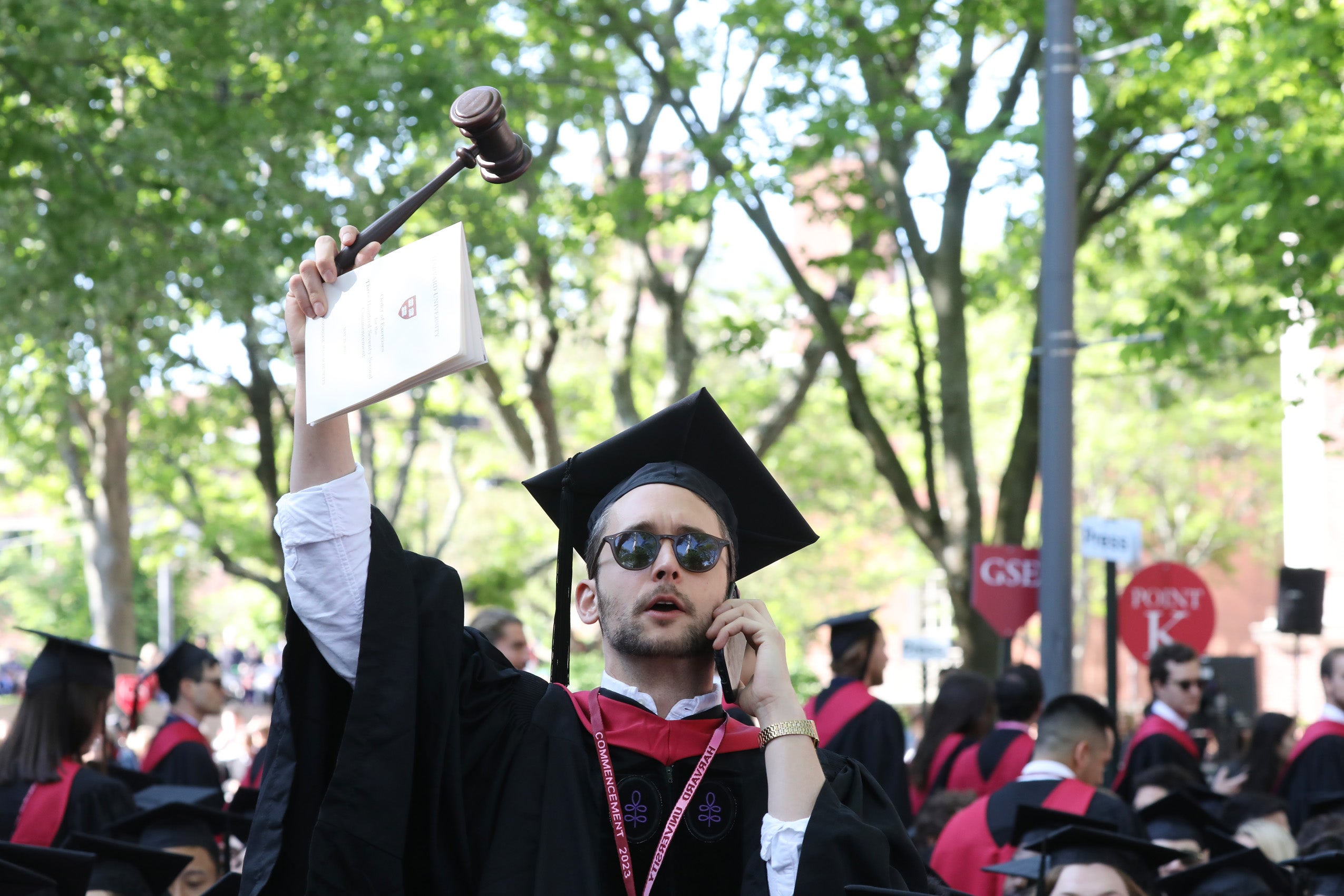 Man wearing regalia holds up his gavel while talking on the phone