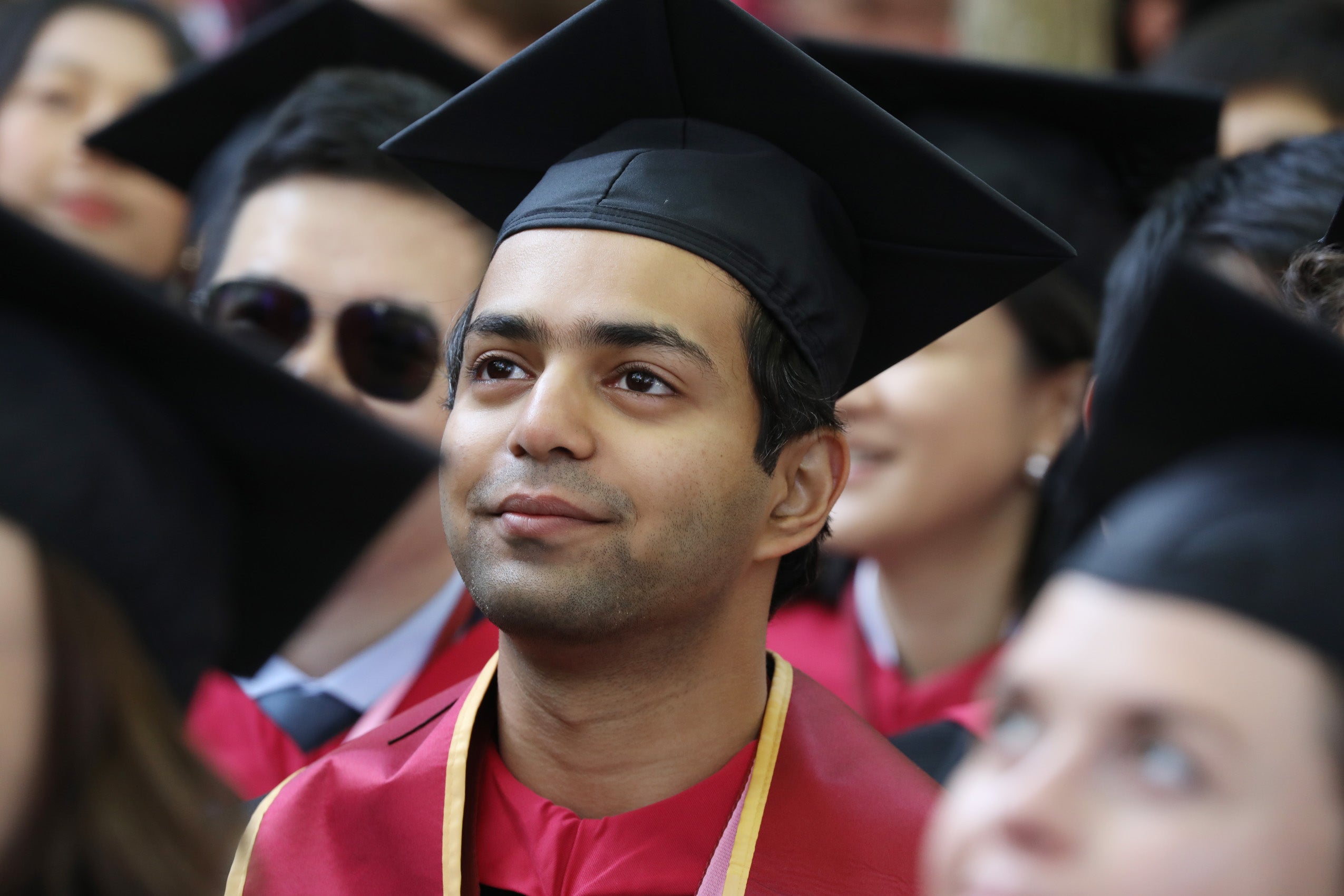 Man in cap and gown watches speaker