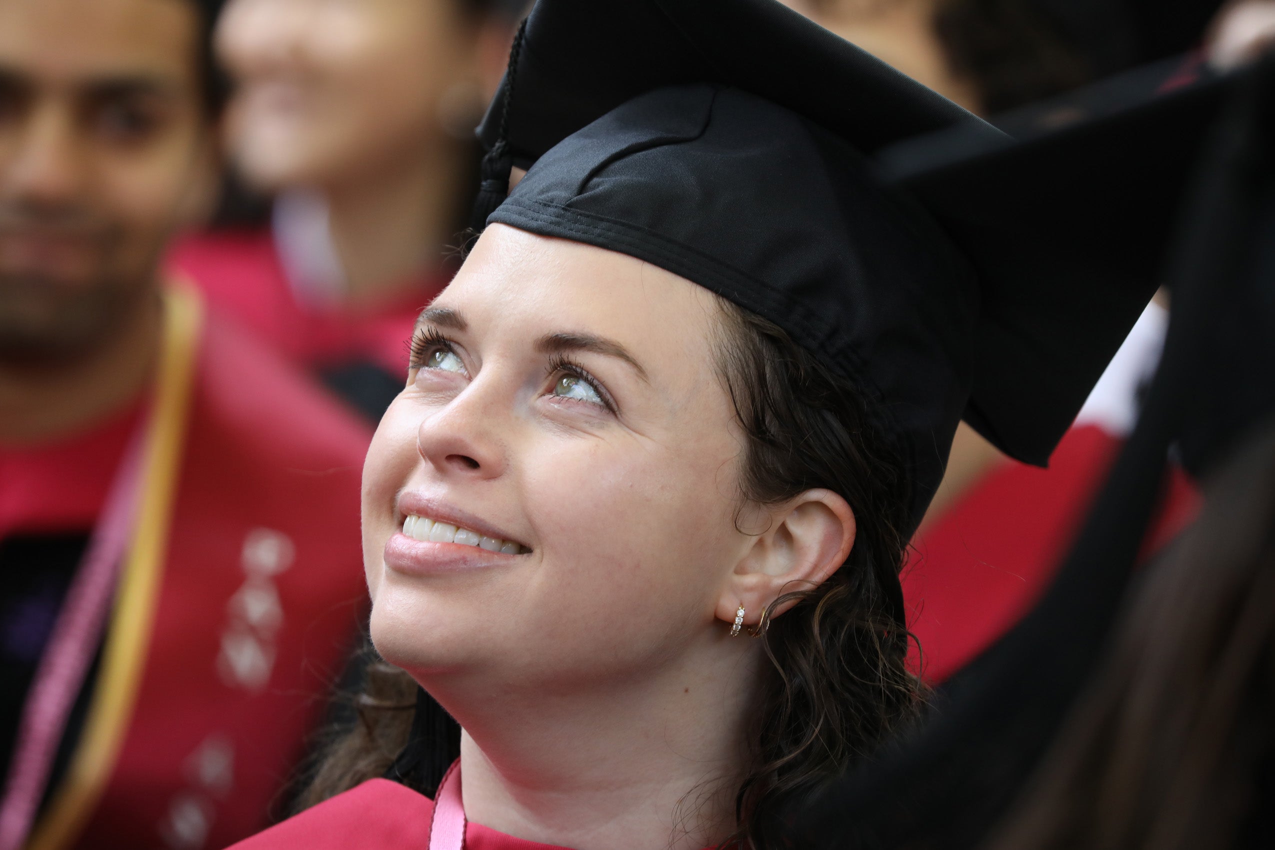 Woman in cap and gown gazes upward