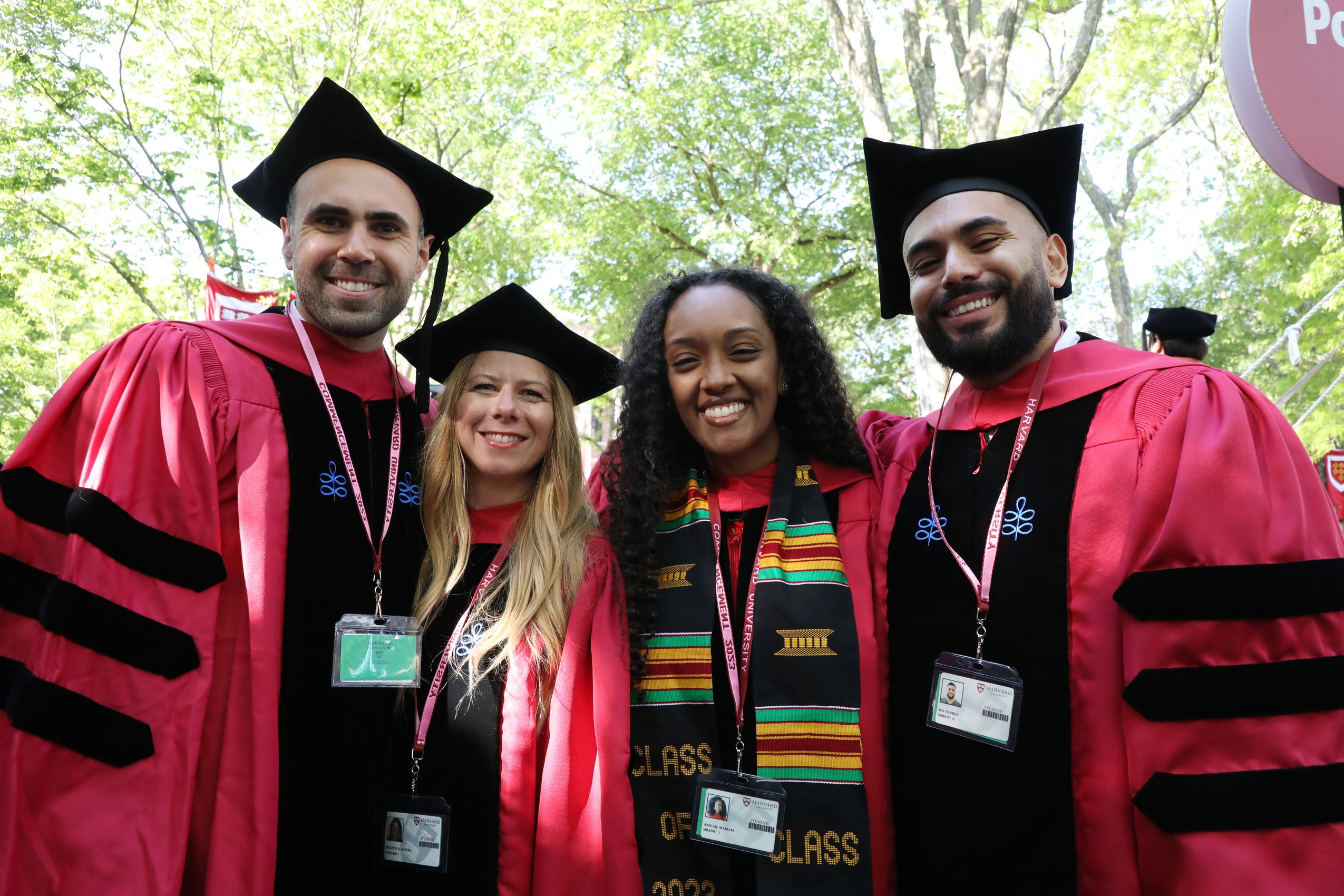 Four graduate students wearing regalia smile