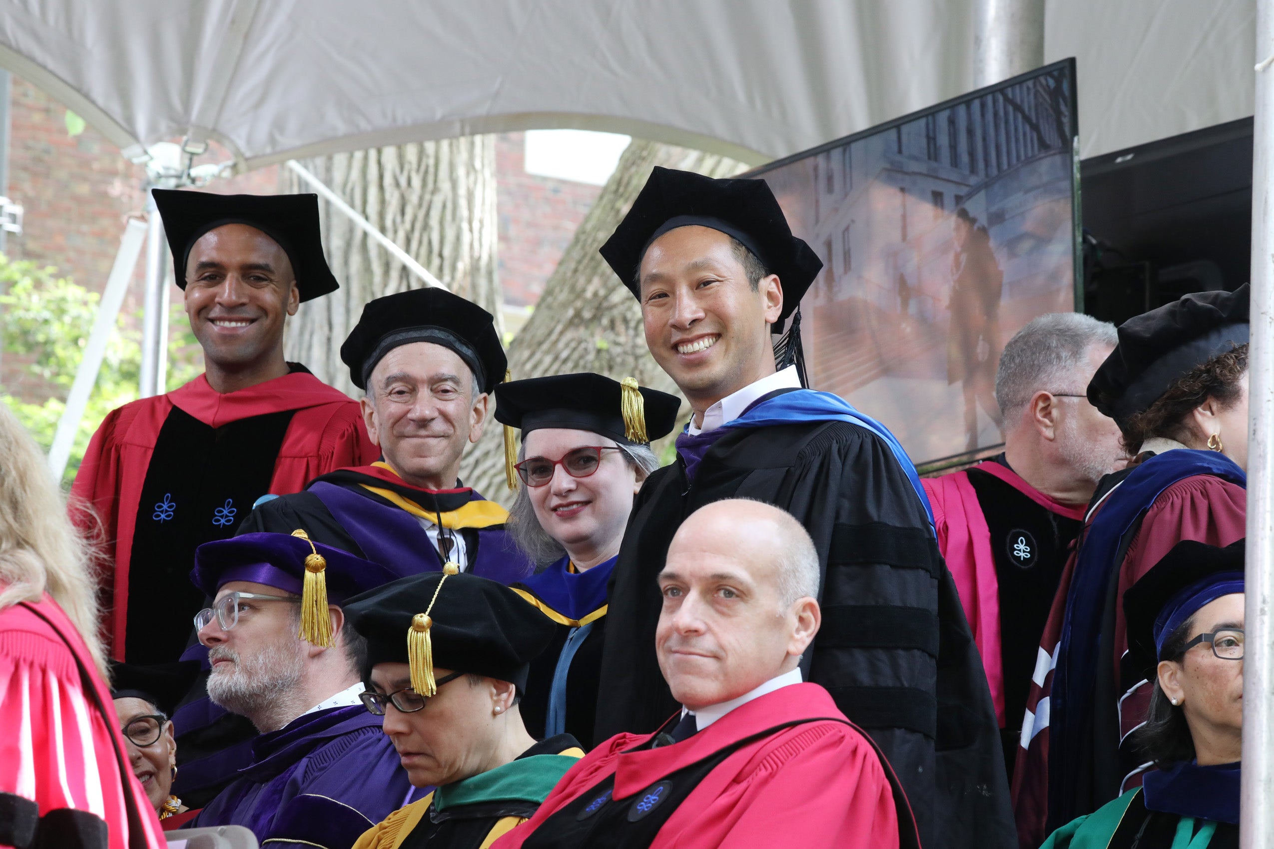 HLS faculty pose from stage at commencement