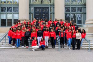 many students in Defenders shirts pose on the steps of Langdell hall
