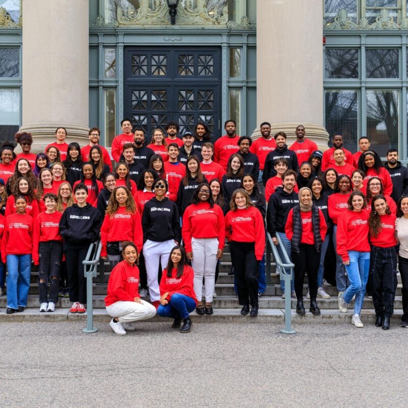 many students in Defenders shirts pose on the steps of Langdell hall