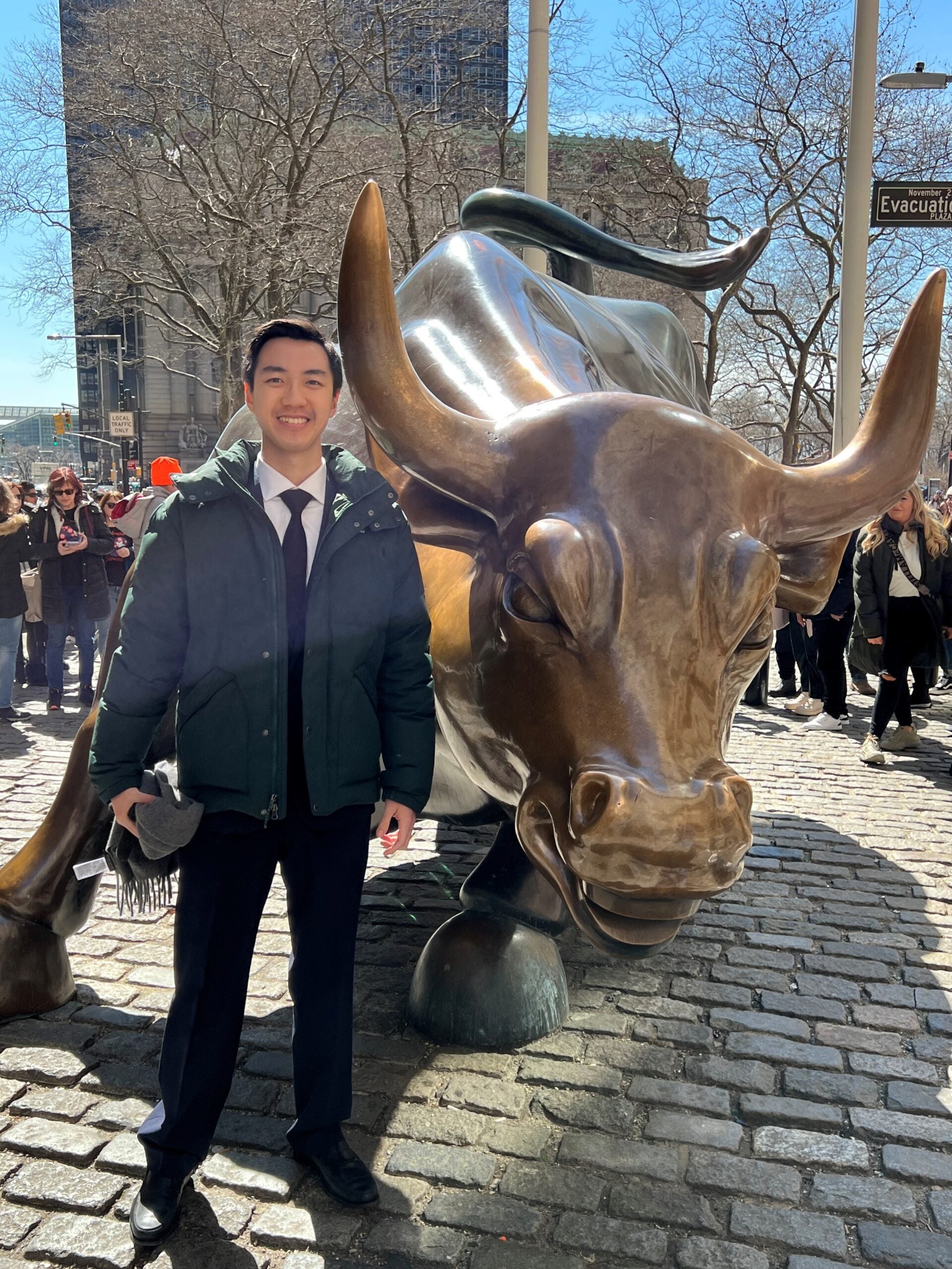 Student Luther Lie in front of Wall Street bull statue