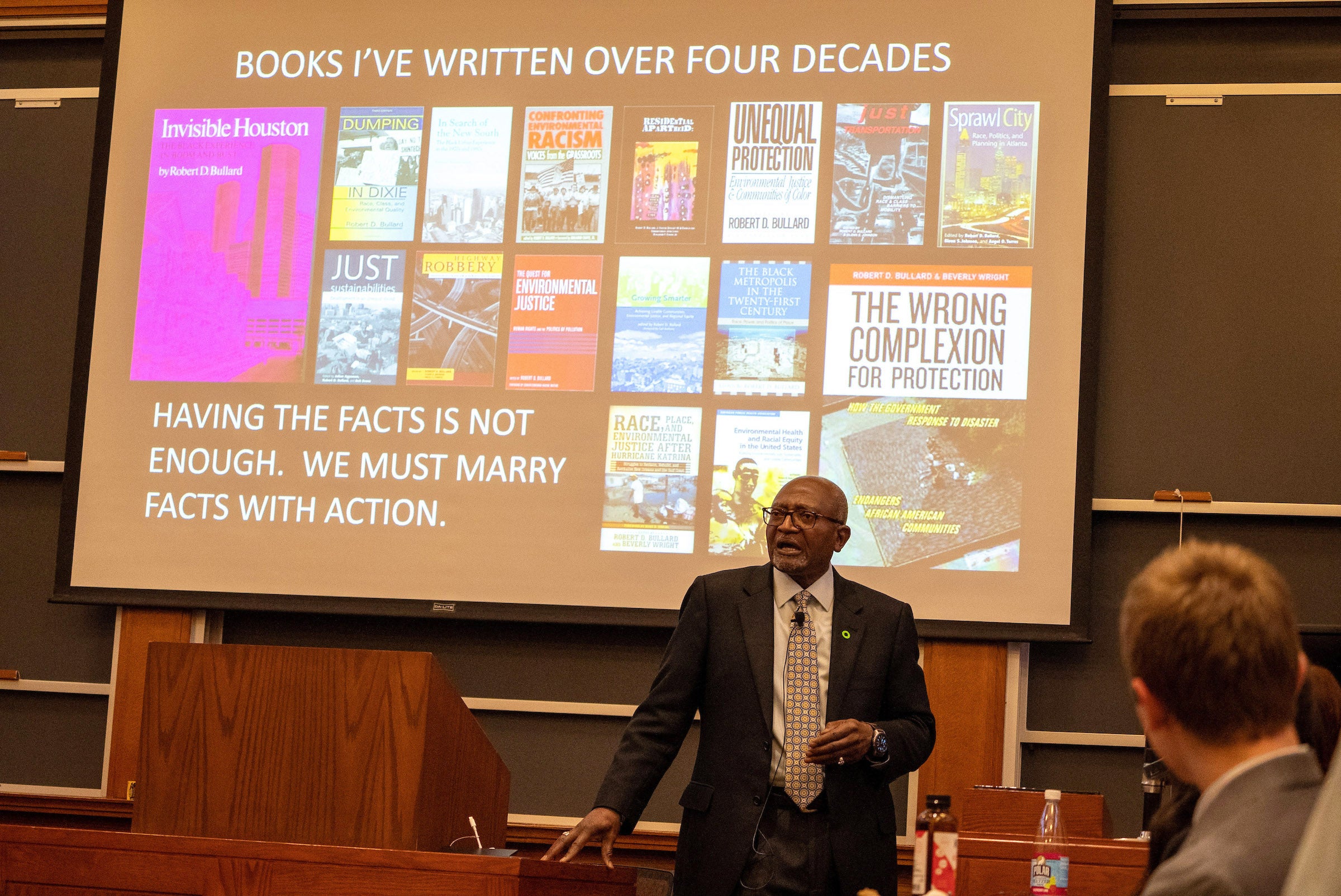 Robert Bullard in front of a slide projecting books he has written.