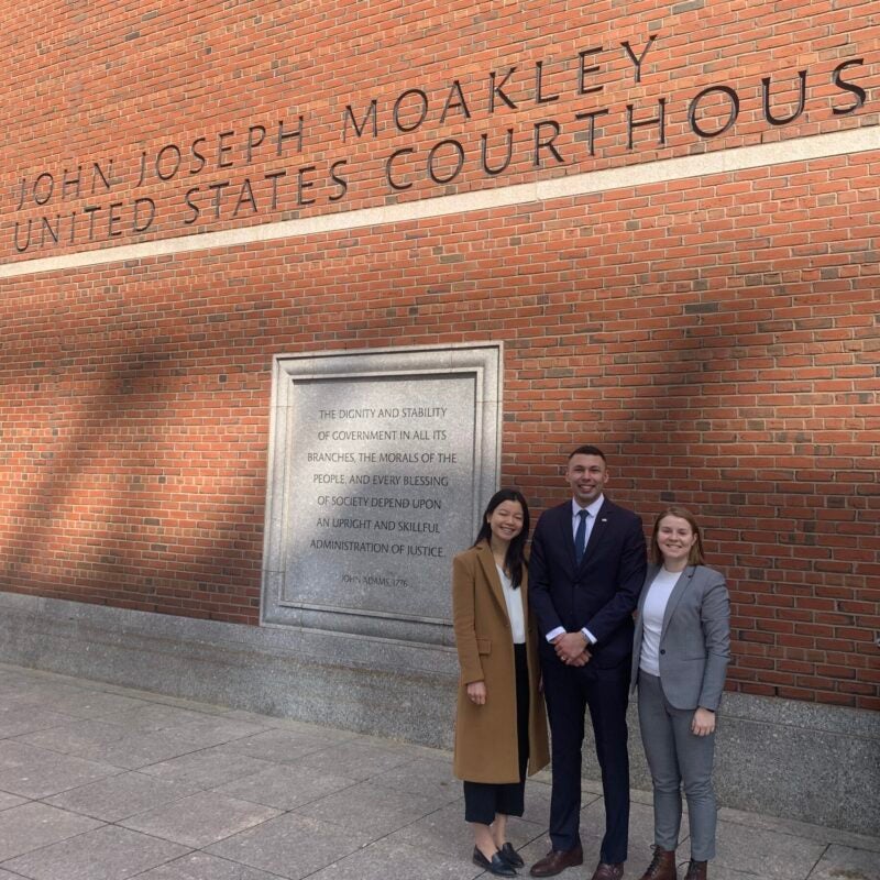 three students stand outside a courthouse exterior