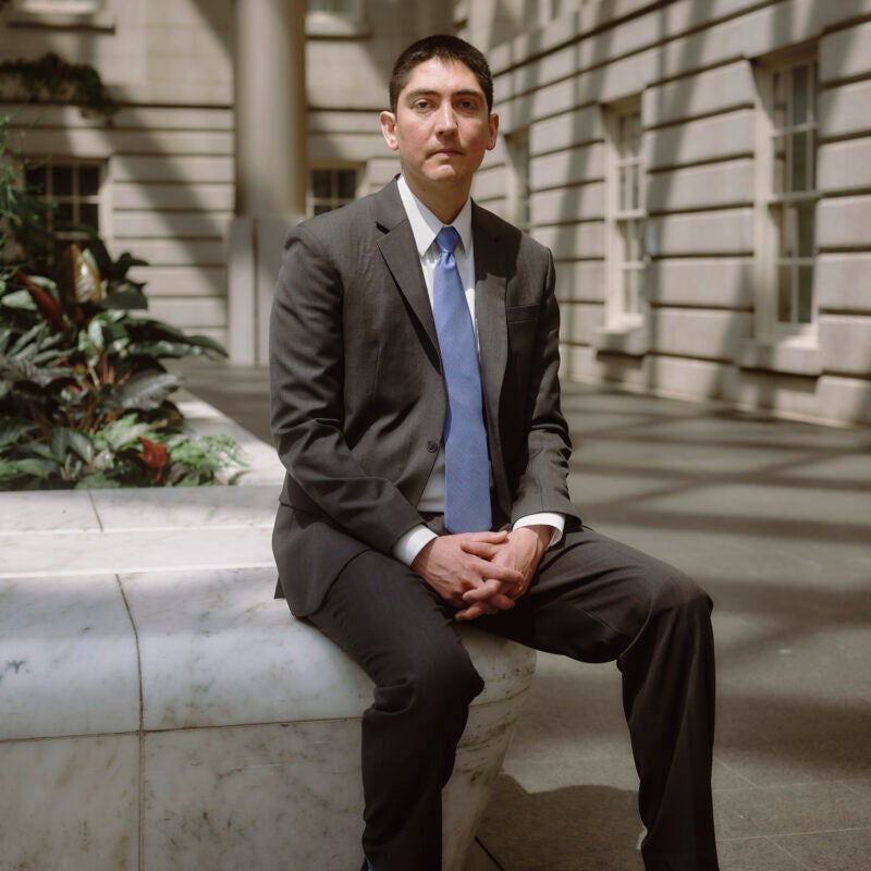 A man sitting on a granite bench in a courtyard