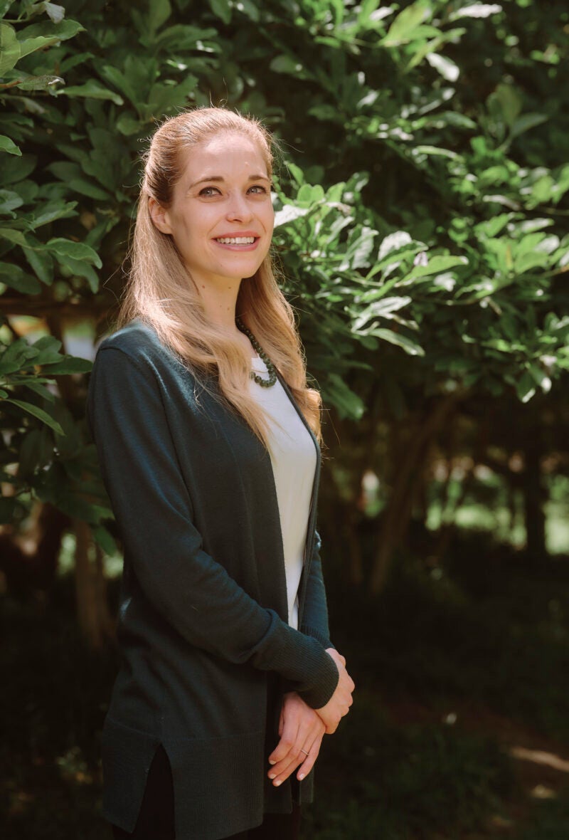 Woman standing in front a green tree