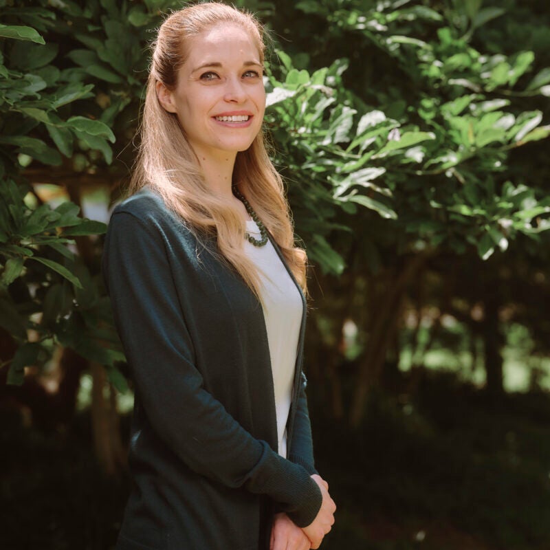 Woman standing in front a green tree