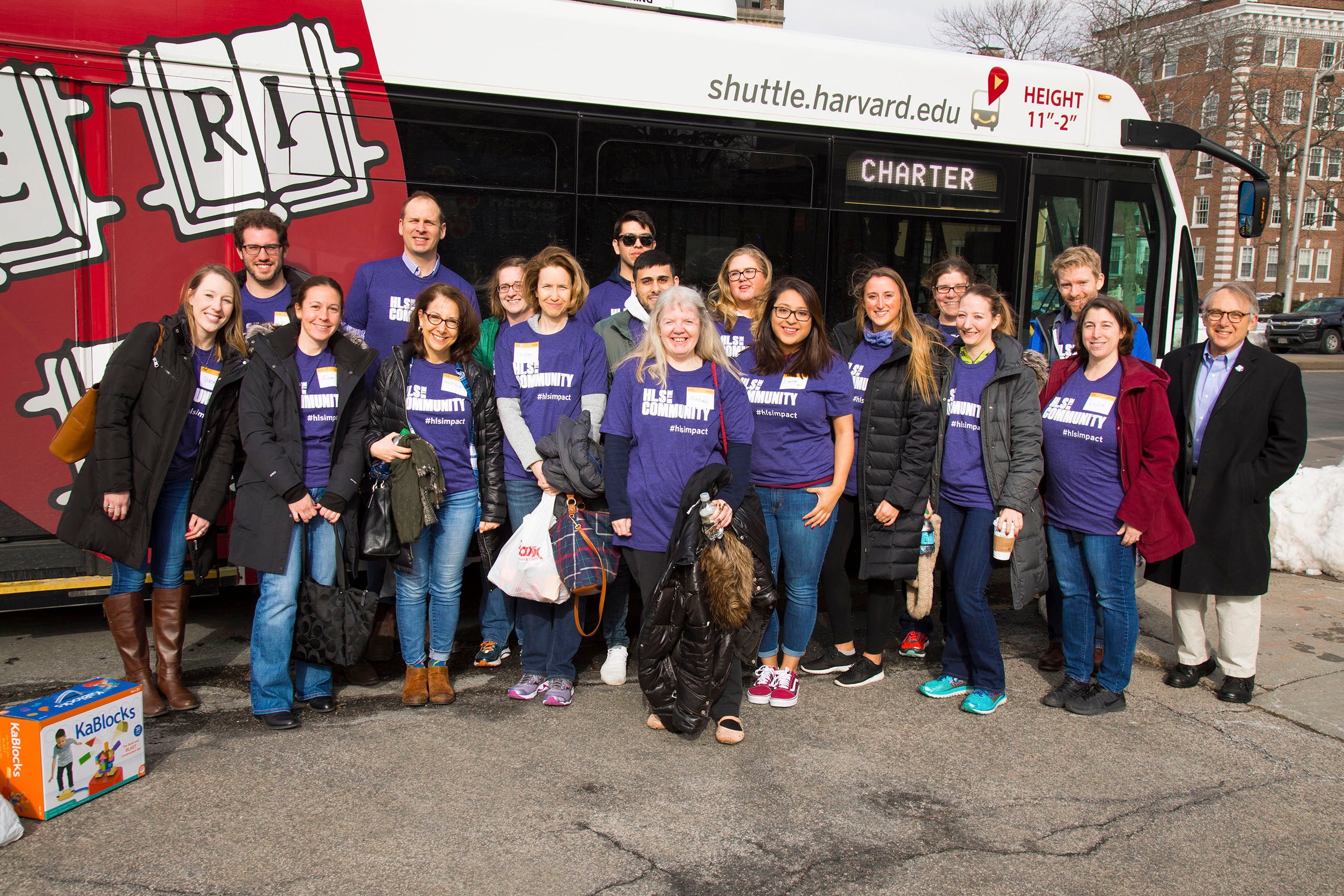group of people standing in front of a bus wearing HLS in the Community shirts
