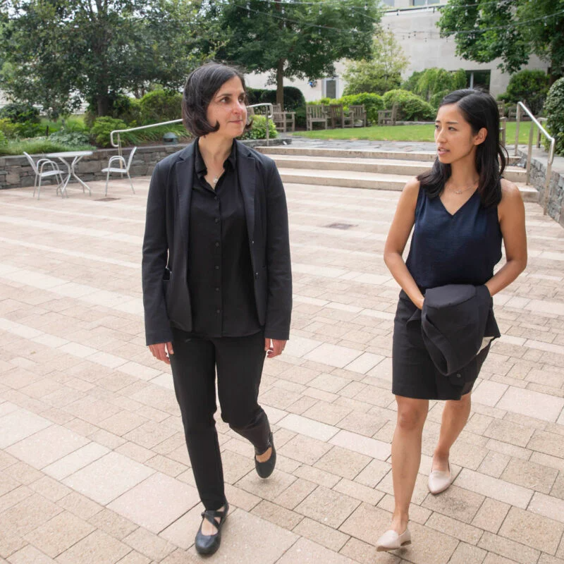 two women walk on a patio