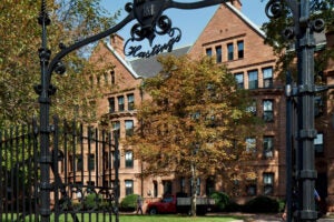 A view of a brick building through the opening in an iron gate which reads Hastings at the top