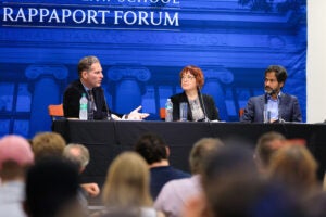 Three people sitting on a panel in front of a blue back drop that reads Rappaport Forum