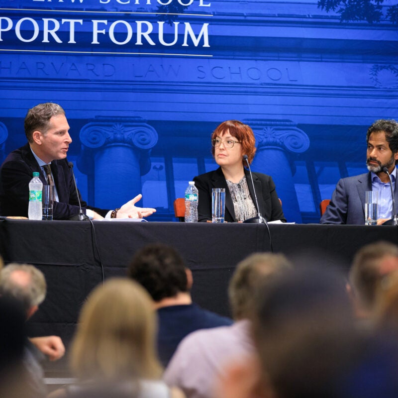 Three people sitting on a panel in front of a blue back drop that reads Rappaport Forum