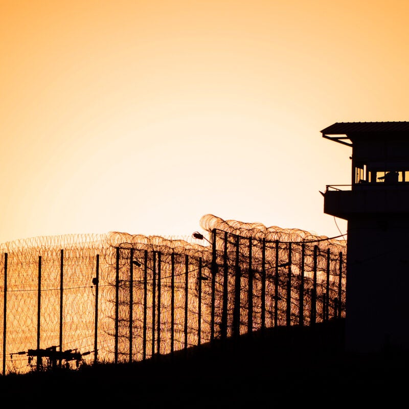 Silhouette of barbed wires and watchtower of prison.