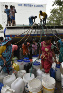 People collect drinking water from a tanker during a water crisis