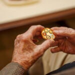 Hands of a man holding a gold coin.
