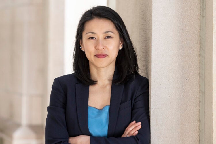 A woman leans on an exterior off-white column
