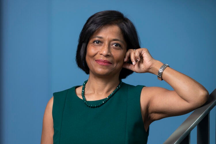 A portrait of a woman in a green dress leaning on the railing of a staircase