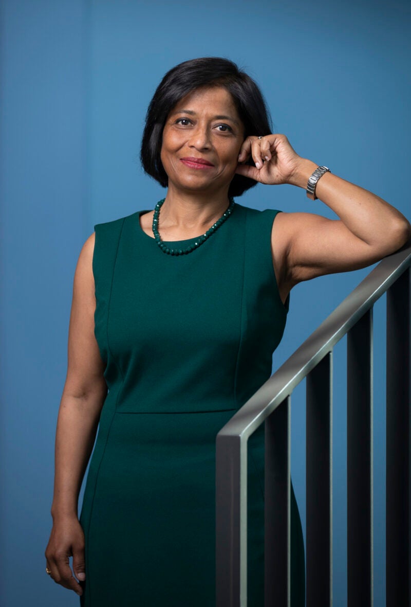 A portrait of a woman in a green dress leaning on the railing of a staircase