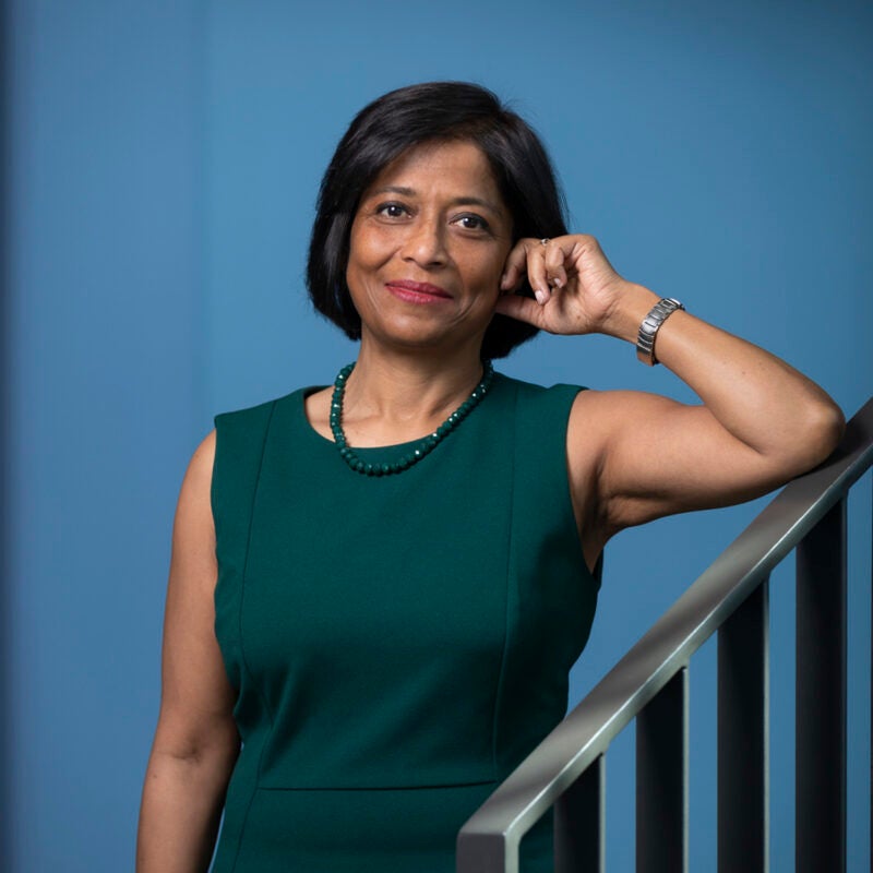 A portrait of a woman in a green dress leaning on the railing of a staircase