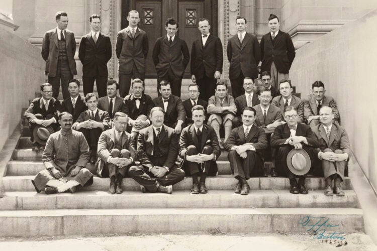 A black and white photo of several rows of men posing for a group portrait on the steps of a building.
