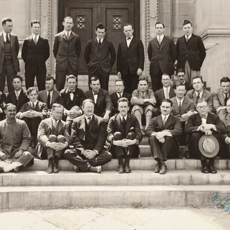 A black and white photo of several rows of men posing for a group portrait on the steps of a building.