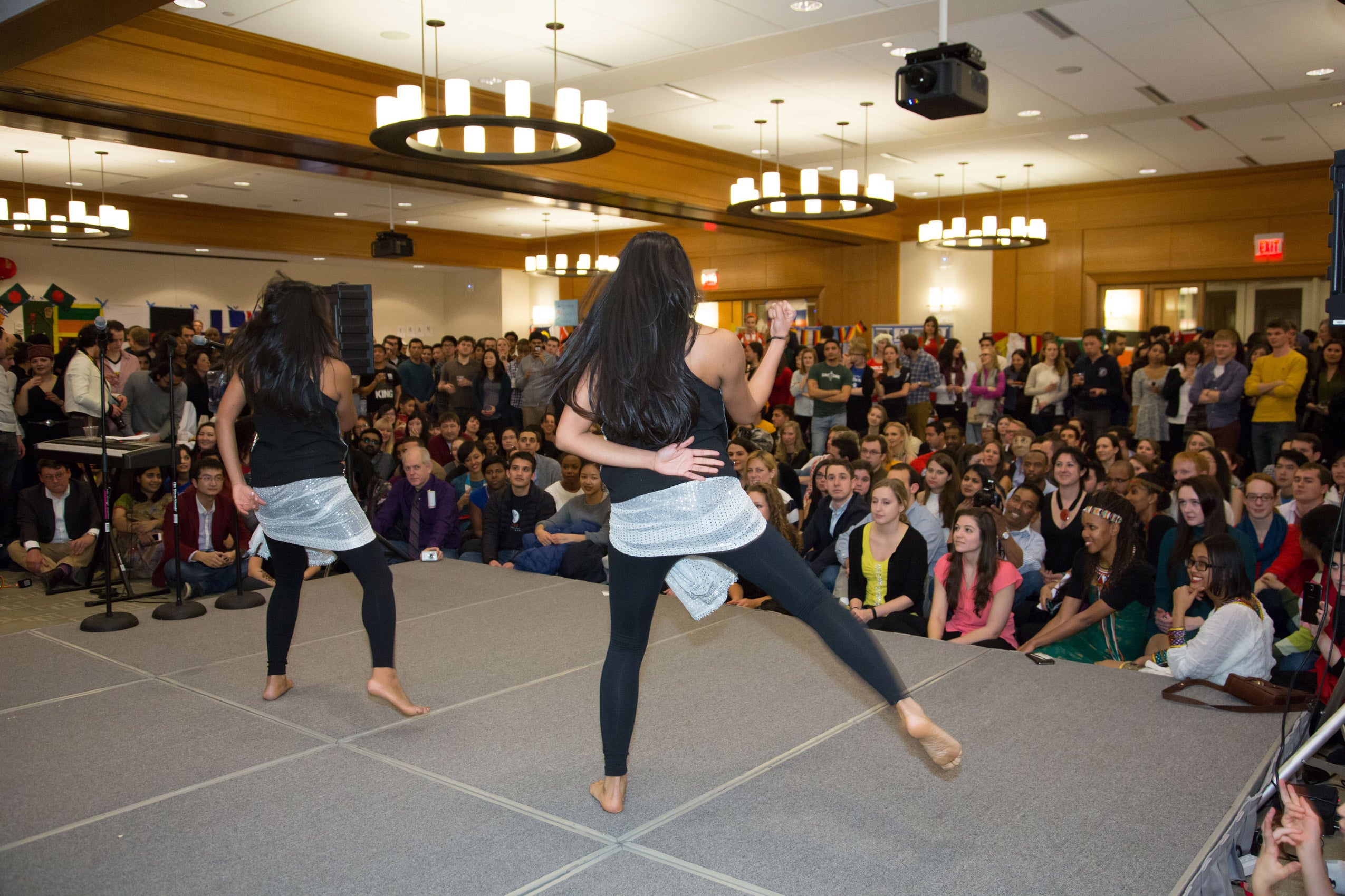 Two women performing on stage as an audience watches