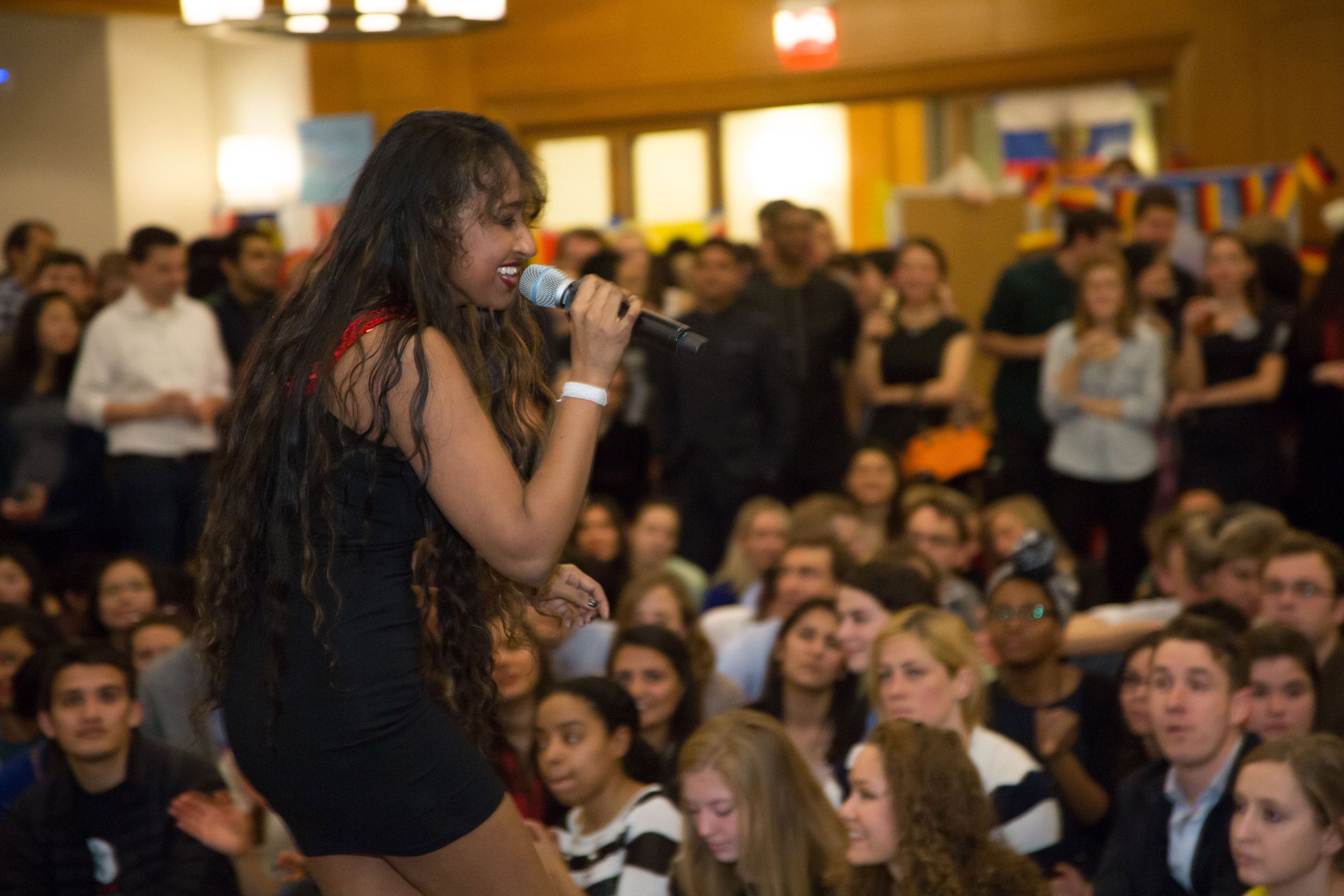 A woman singing into a microphone on stage as an audience watches on