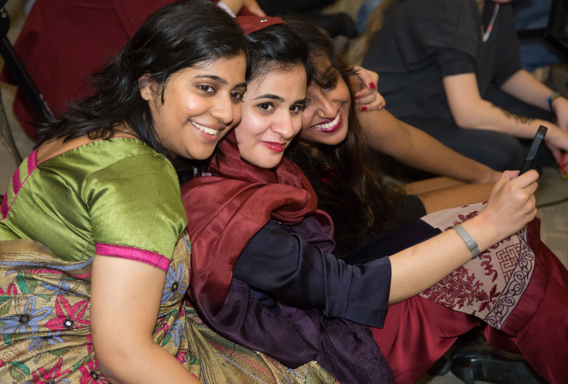 A group of three women sitting on the floor and posing together