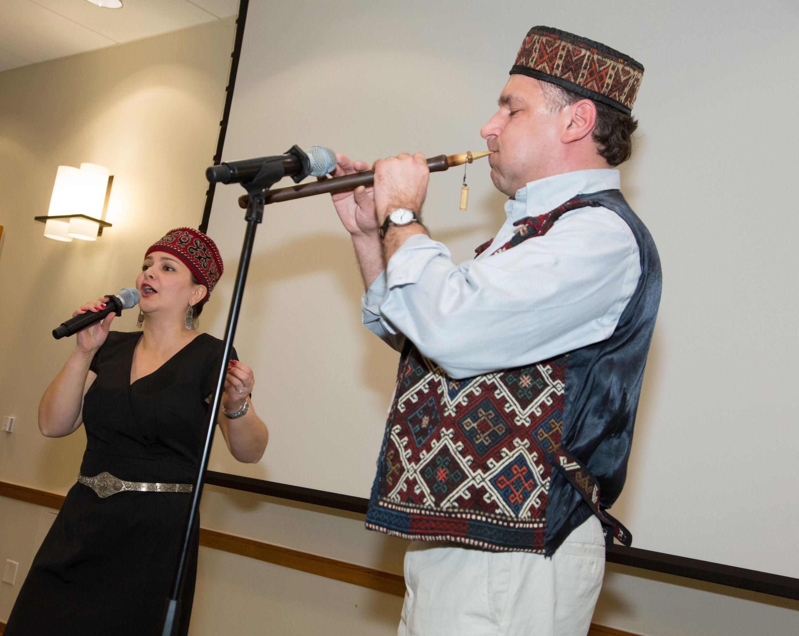A man performing with an instrument and a woman singing into a microphone