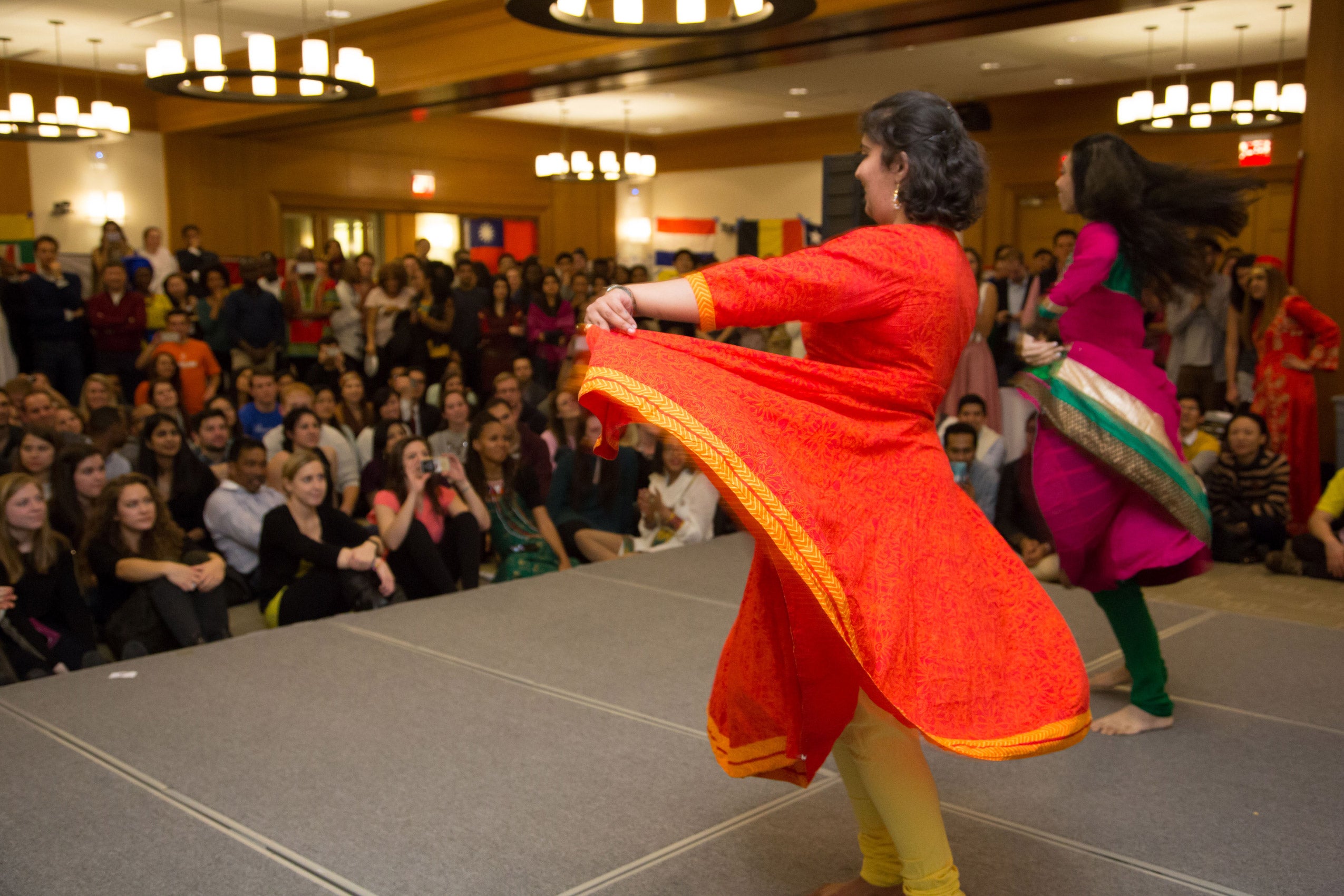 Two women performing on stage as an audience watches
